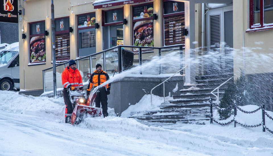 To medarbeidere hos Hoemgruppen rydder snø ved et av hotellene i Haugata i Kristiansund.