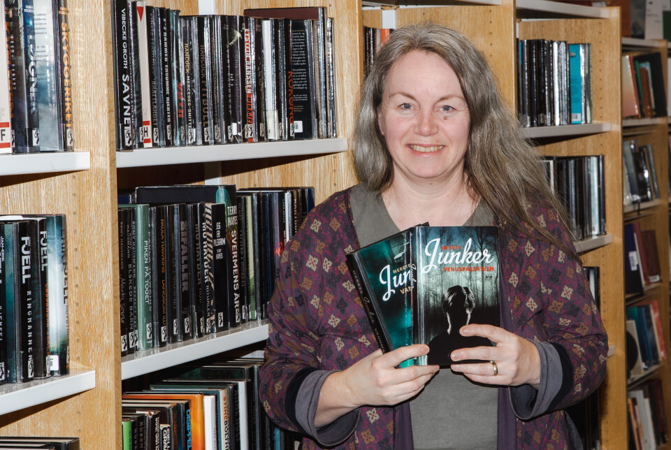 Merete Bratsberg Aae, som er biblioteksjef i Averøy. med noen av de mest utlånte bøkene i krimhyllen på Averøy bibliotek.