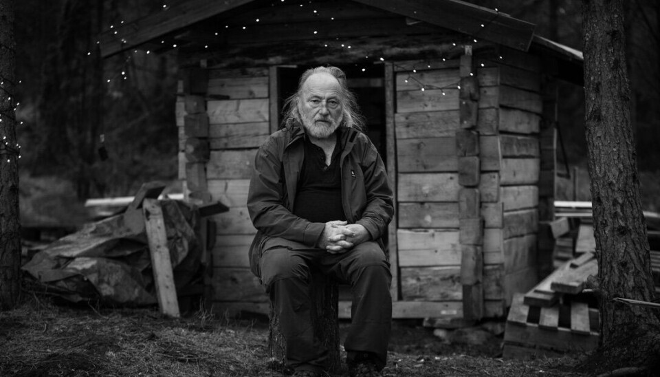 Footografi av Arne Fjellstad ved den lille tømmerkoia som han har brukt til å lære seg lafting på egen hånd.