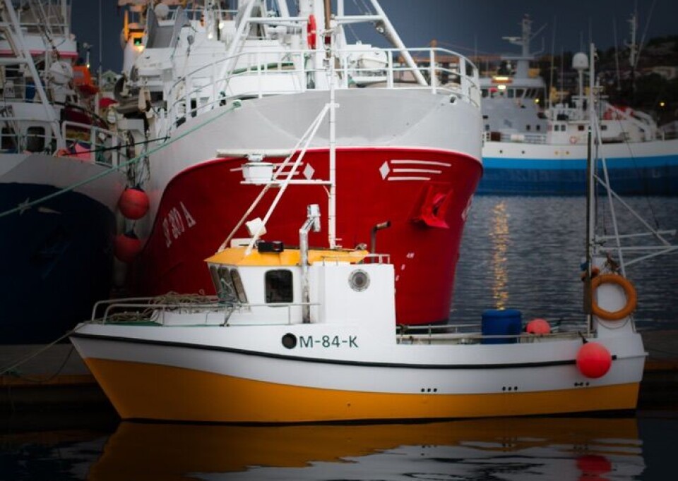 En liten sjark foran fiskebåter på havna i Kristiansund.