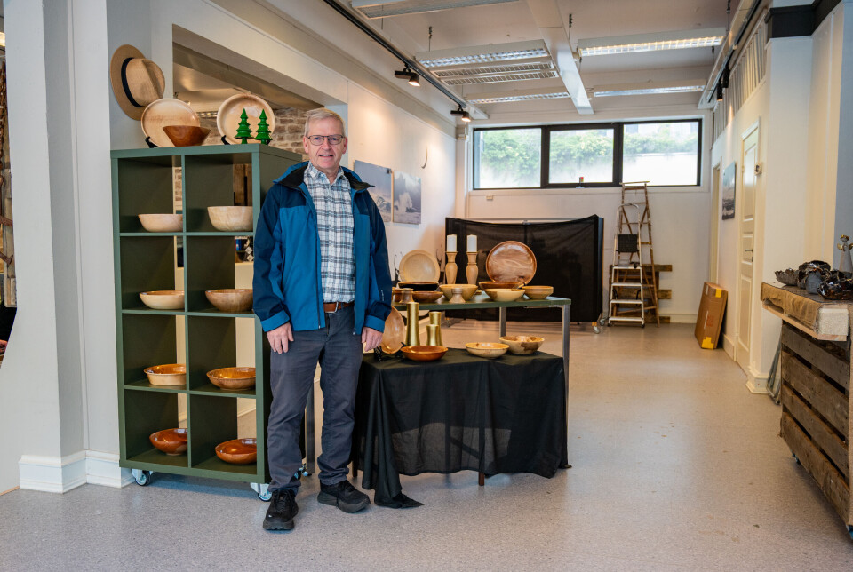Øivind Hatlen viser frem utskårne fat, skåler og andre treprodukter.