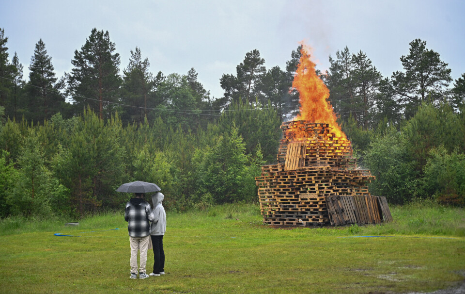 Et par står å nyter bålet i regnet.