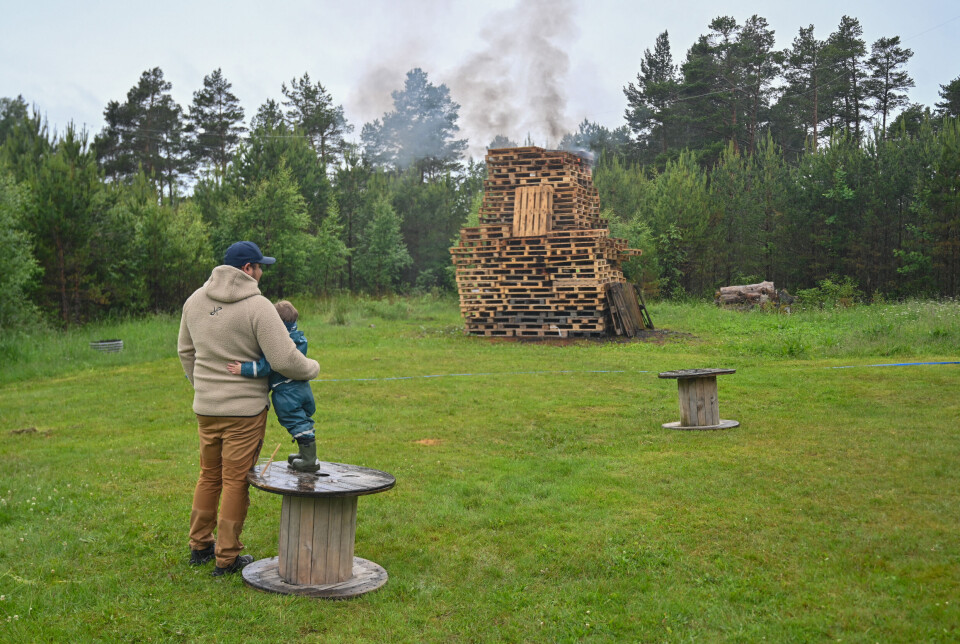 Far og sønn ser på bålet som har blitt tent.