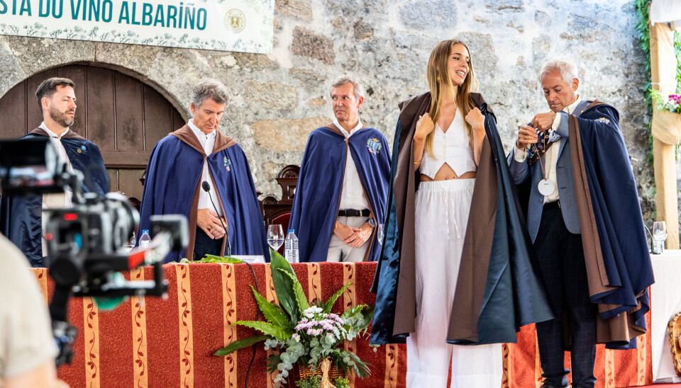 Skuespilleren María Mera Consuegra blir utnevnt til Dona do Albariño i den prestisjefylte Orden de los Cabaleiros e Donas do Albariño, under en lukket seremoni i borggården på det historiske slottet Pazo de Fefiñáns i Cambados. I bakgrunnen står Samuel Lago Ozón, ordfører i Cambados (PSOE), Alberto Núñez Feijóo, stormester i ordenen og leder for Partido Popular, og Alfonso Rueda, president i Galicia og også representant for Partido Popular – alle iført seremonikapper og medaljonger som tegn på sine roller i brorskapet.